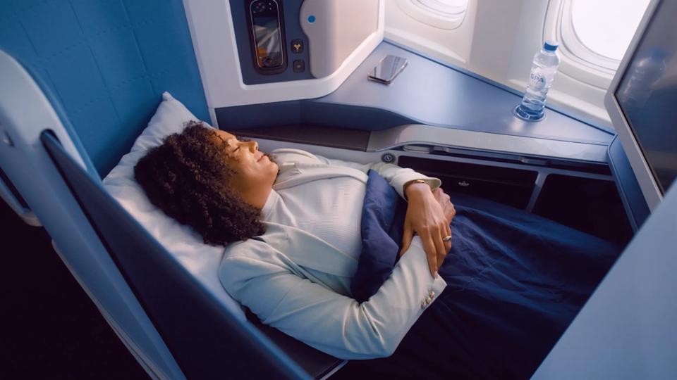 Woman sleeping comfortably in a fully flat World Business Class seat